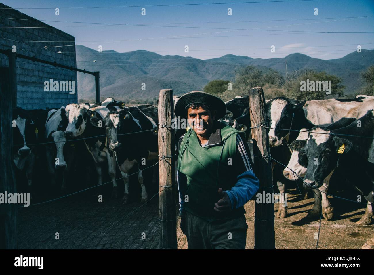 Farmworker smiles at the camera. This dairy is located in the outskirts of Salta, Argentina and has around 800 cows. Female cows are artificially inseminated for the first time at the age of 15 months. A cow's pregnancy, is like a human's, lasts nine months. Once the calf has been born, the cow is milked daily by the machine. On average, six to eight weeks after the birth of the calf, the cow is inseminated again. After about 5-6 years she stops giving milk and the animal is slaughtered. (Photo by Lara Hauser/SOPA Images/Sipa USA) Stock Photo