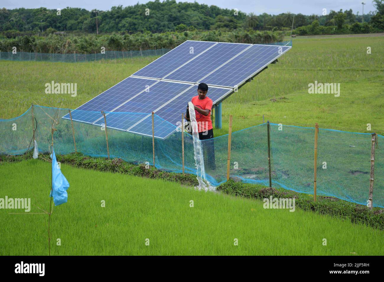 Ripan Deb, a 37 year old farmer putting water to his field through a solar-powered water pump which was installed in his field with the help of the Government of Tripura’s subsidised policy in Gokulnagar, Agartala. Tripura, India. Stock Photo