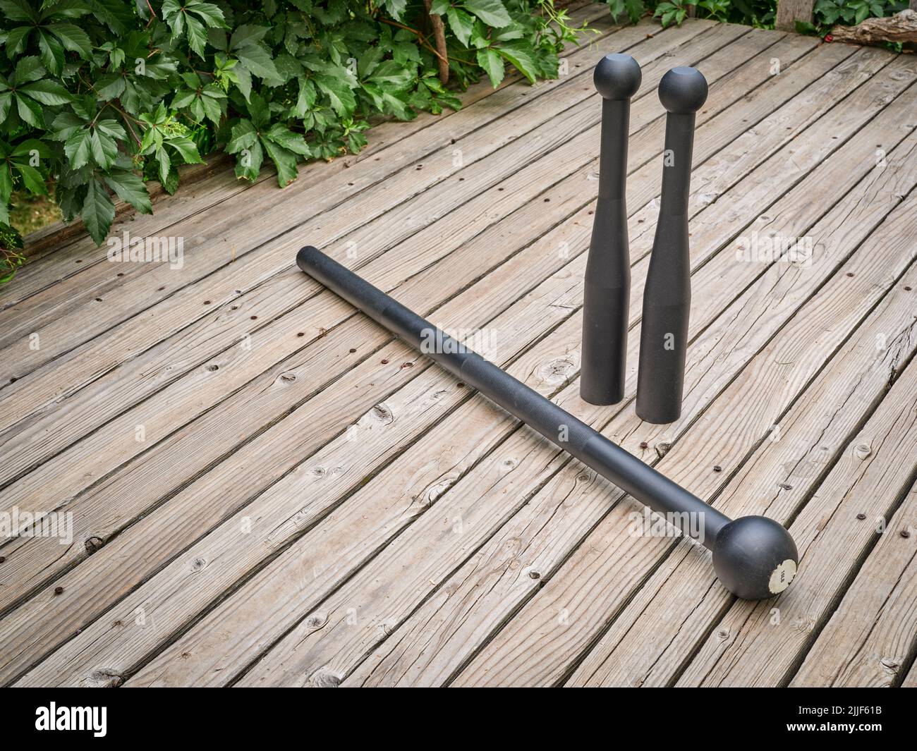 steel mace and clubs on a backyard deck, functional fitness concept
