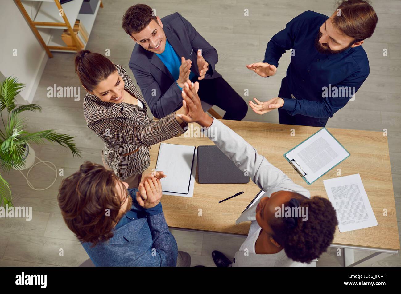 Diverse team of people close successful business deal and give each other high five Stock Photo