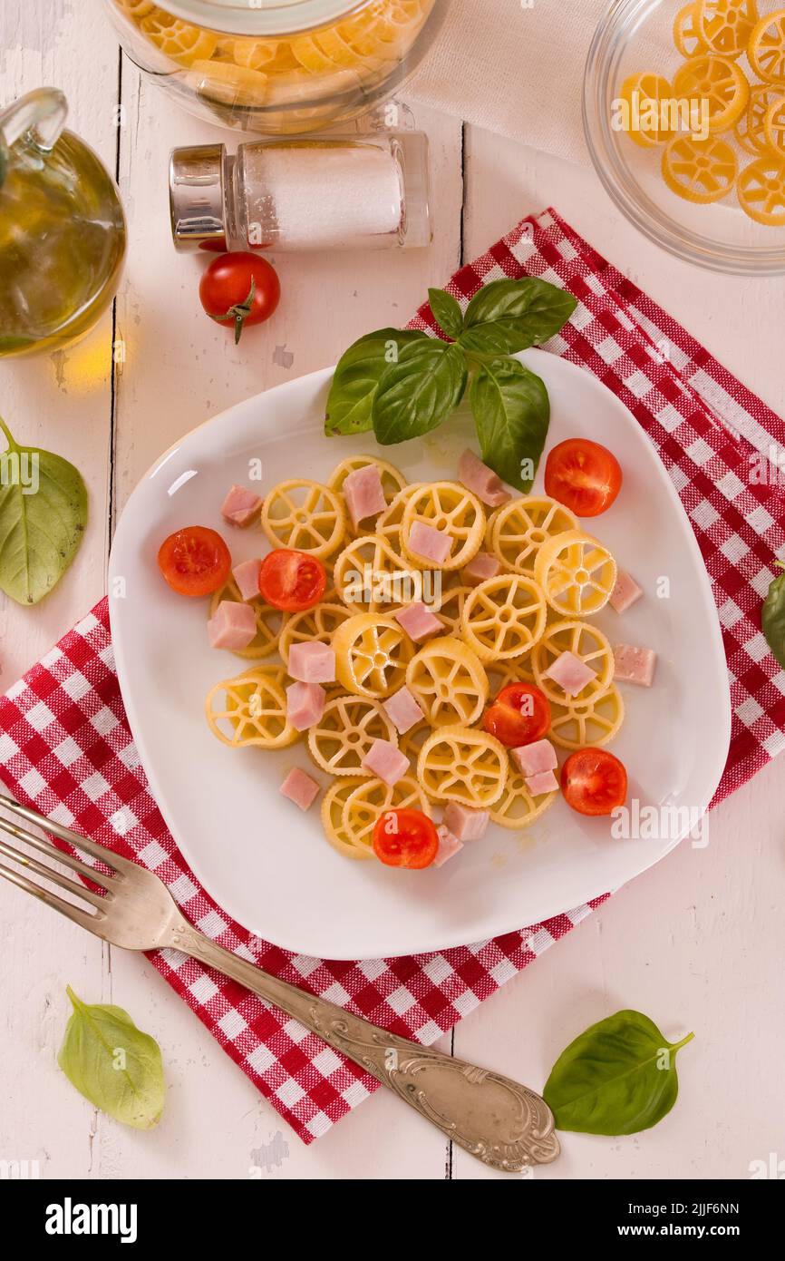 Ruote pasta with tomato and ham. Stock Photo