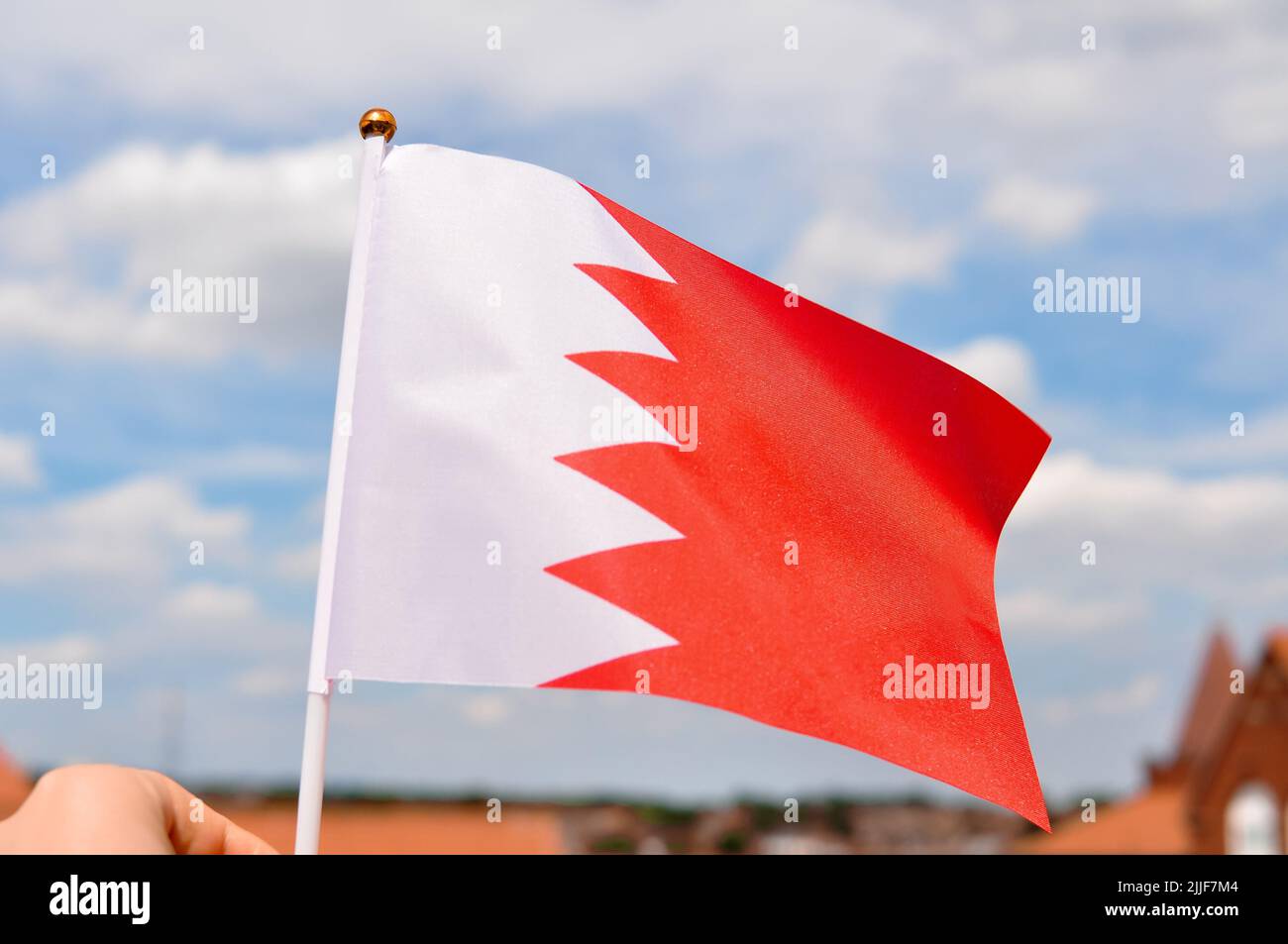 close up of national flag of bahrain on blue sky background ,red and white colors . Stock Photo