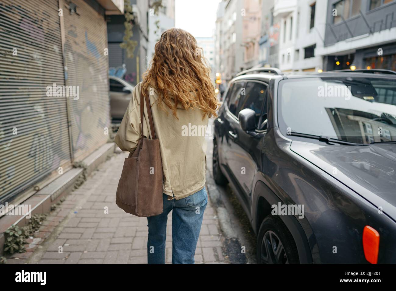 Young beautiful pretty woman walking along the street in modern city ...