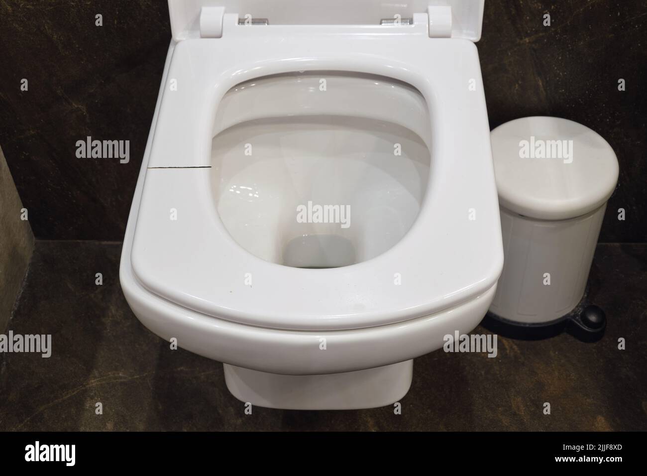 Cracked white toilet seat. A broken seat in the home toilet Stock Photo