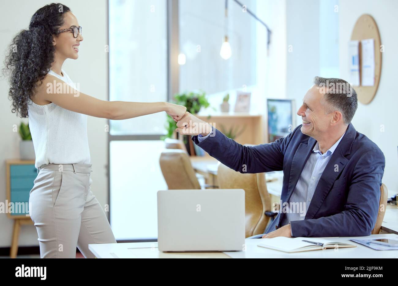Put it there. two young businesspeople giving each other a fist bump in