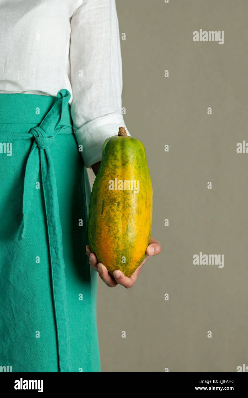 Close-up of a woman holding a papaya against plain background - stock photo Stock Photo
