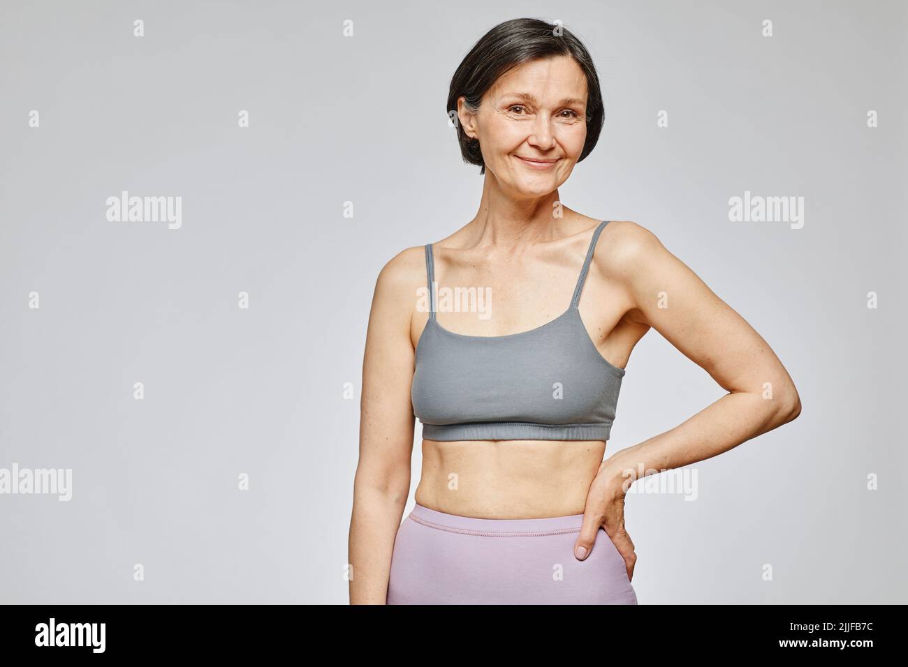 Minimal waist up portrait of smiling mature woman wearing neutral underwear  against grey background, body positivity concept, copy space Stock Photo -  Alamy