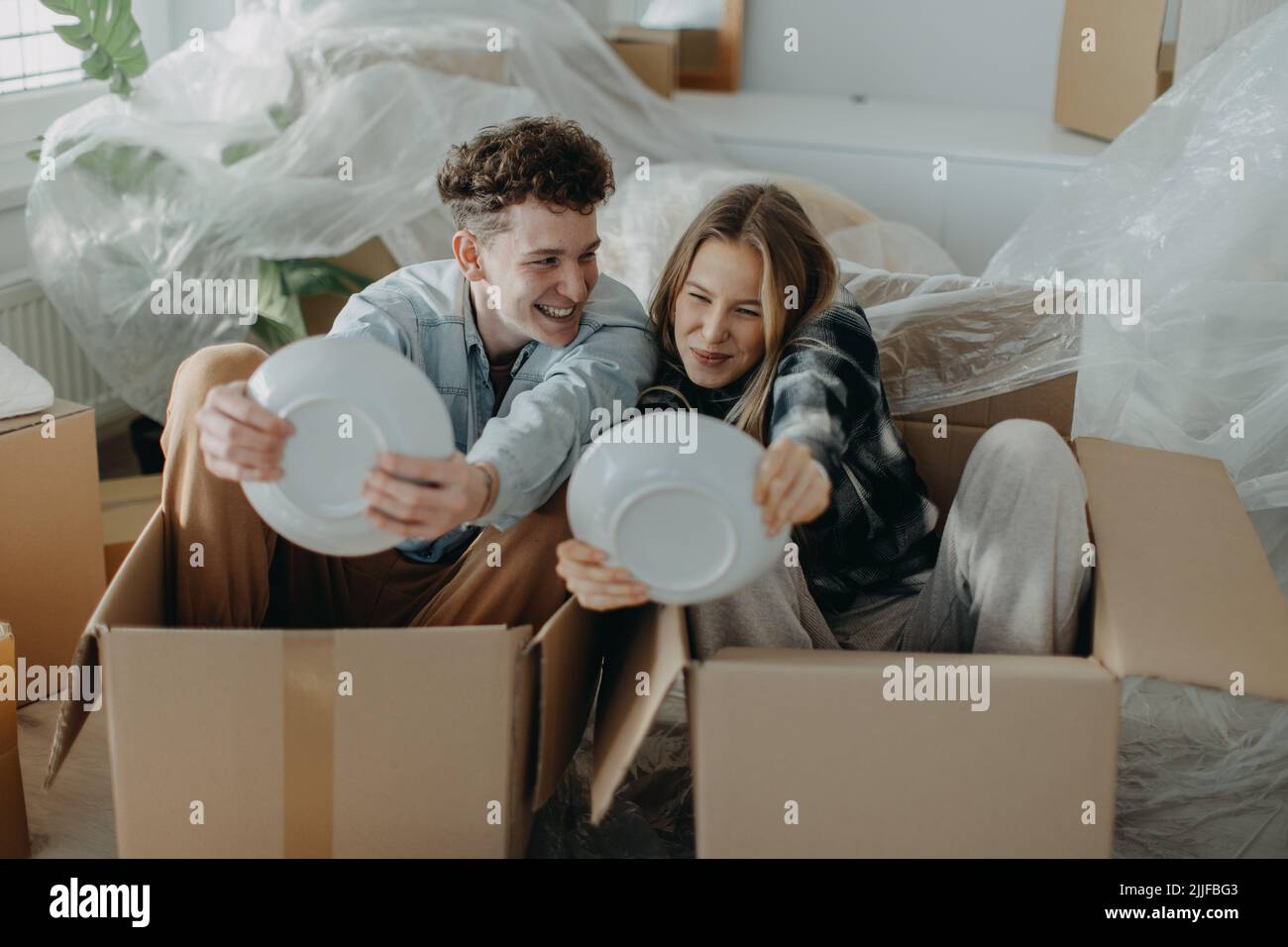 Cheerful young couple in their new apartment, having fun when unpacking ...