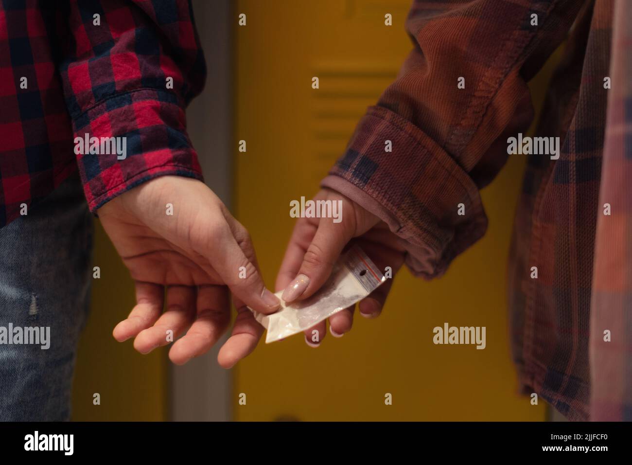 Unrecognizable high school students dealing drugs in shool corridor. Stock Photo