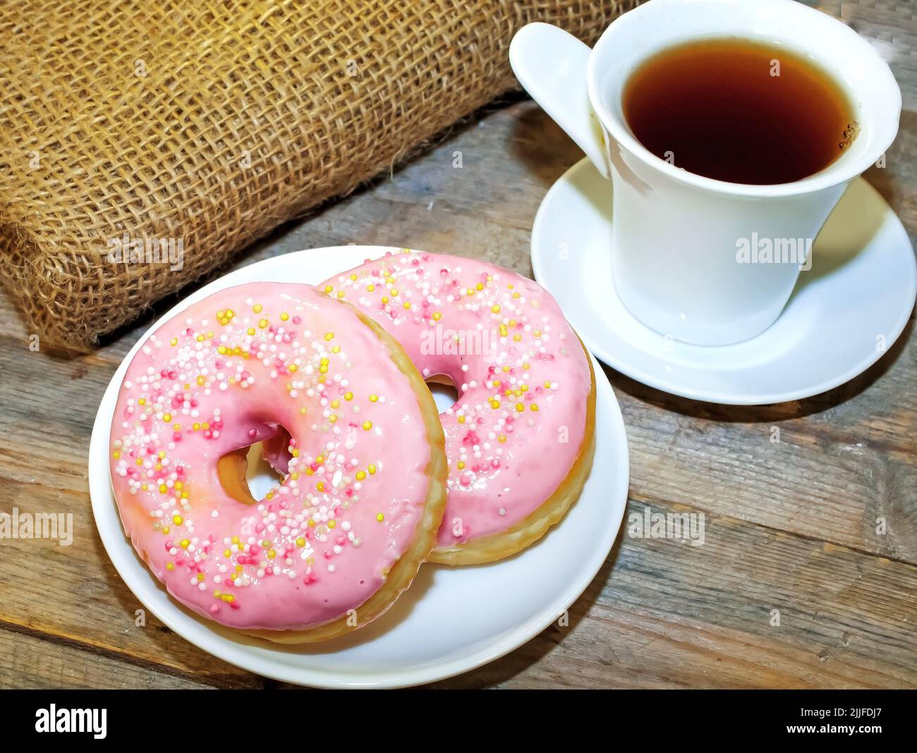 Sweet tasty donuts with sprinkling and fragrant tea. Stock Photo
