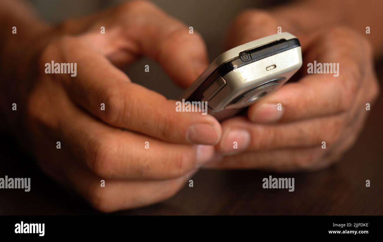 A button phone in the wrinkled hands of an elderly person Stock Photo
