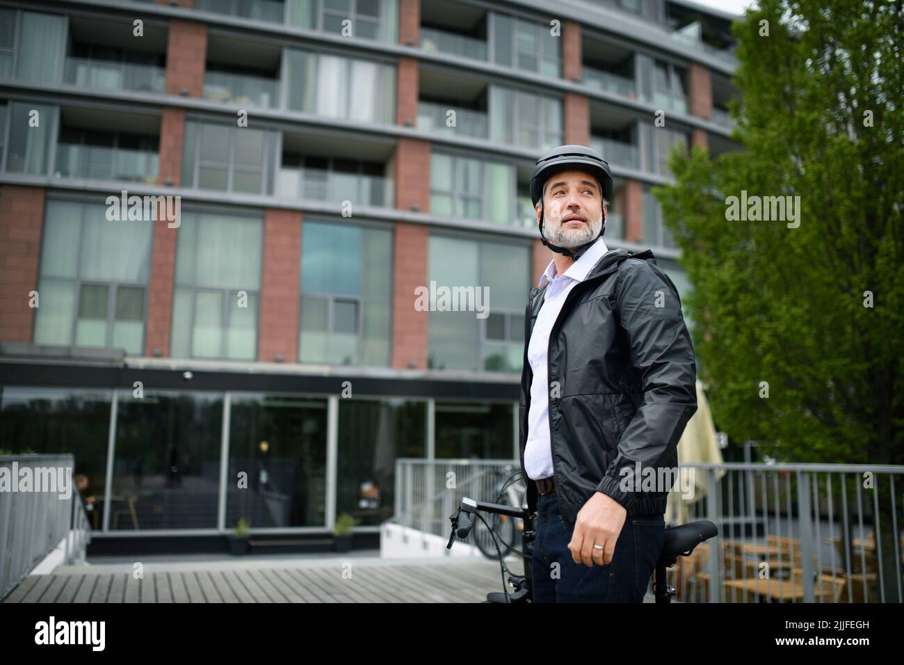 Businessman commuter on the way to work, pushing bike, sustainable lifestyle concept. Stock Photo