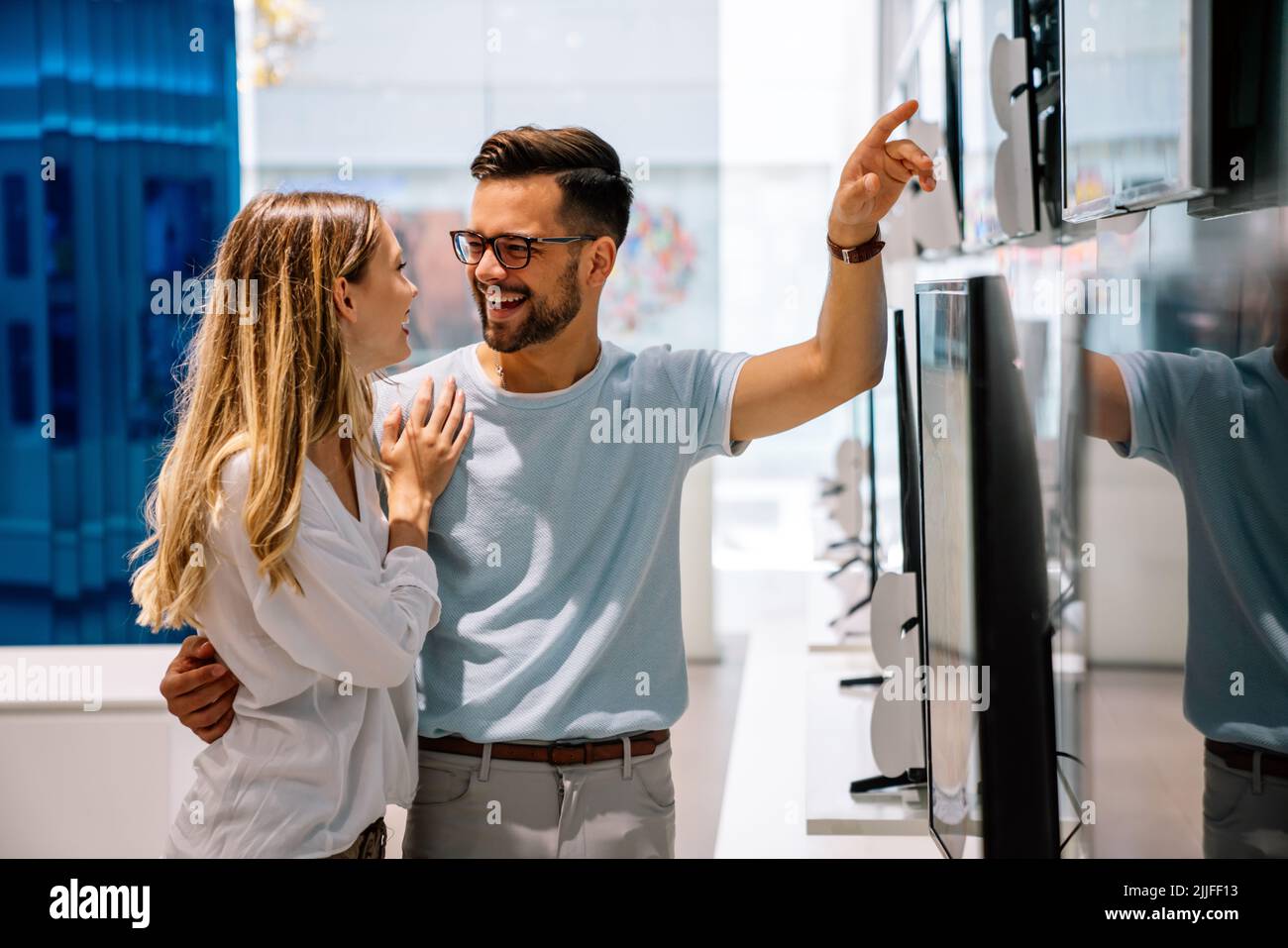 Happy people in consumer electronics retail store looking at new digital device Stock Photo