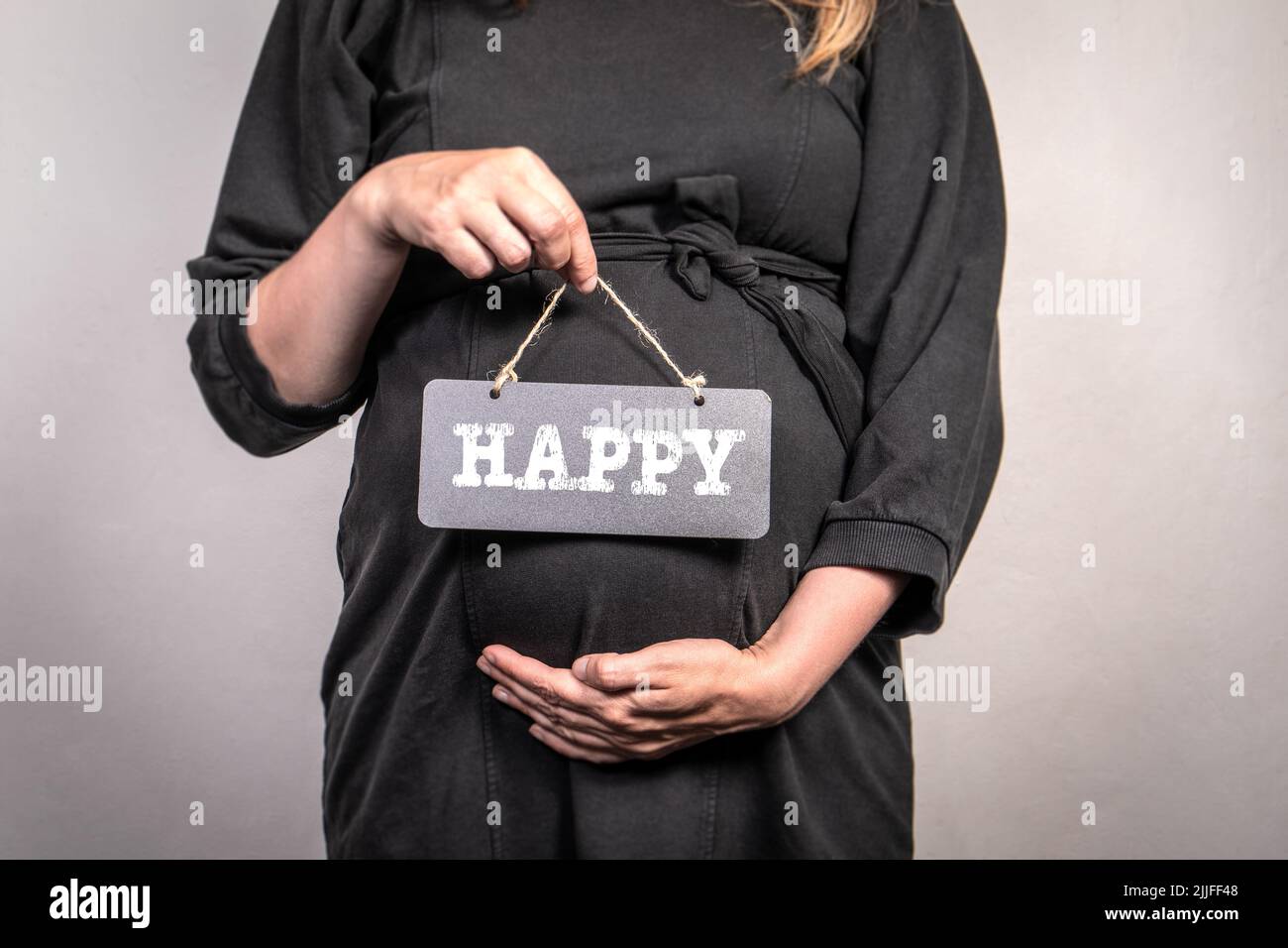 Happy, woman's health and happiness concept. Pregnant, black dress and chalk board. Stock Photo