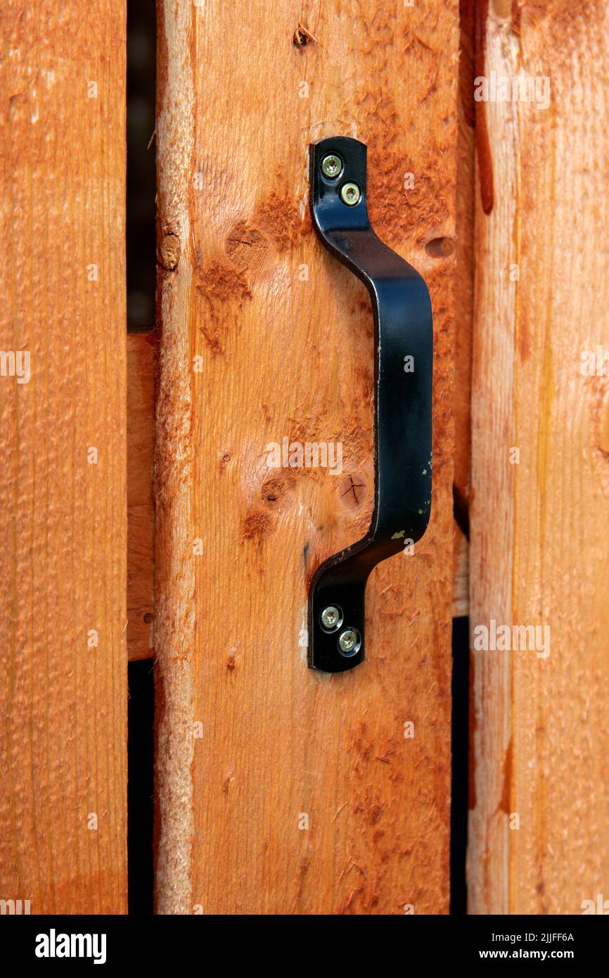 Black door handle on wooden plank door. Architectural details in countrystyle.. Stock Photo