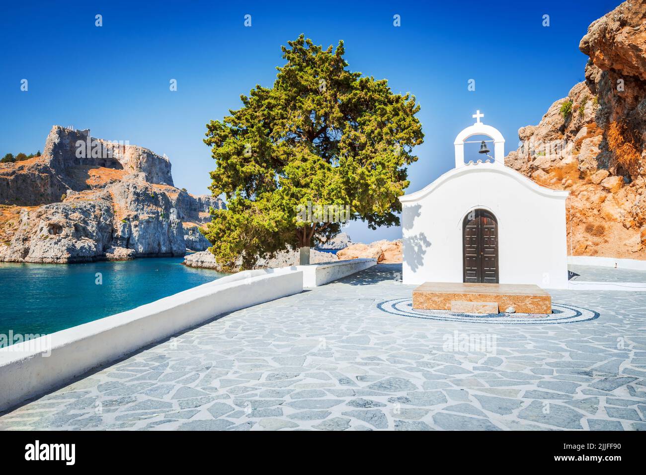 Rhodes, Greece. Saint Paul bay with white chapel. Aegean Sea landscape with ancient town of Lindos and Acropolis rocky ruins. Stock Photo