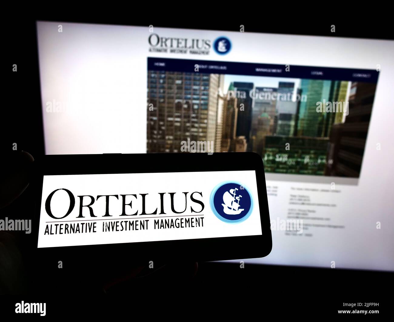 Person holding smartphone with logo of US hedge fund company Ortelius Advisors LP on screen in front of website. Focus on phone display. Stock Photo