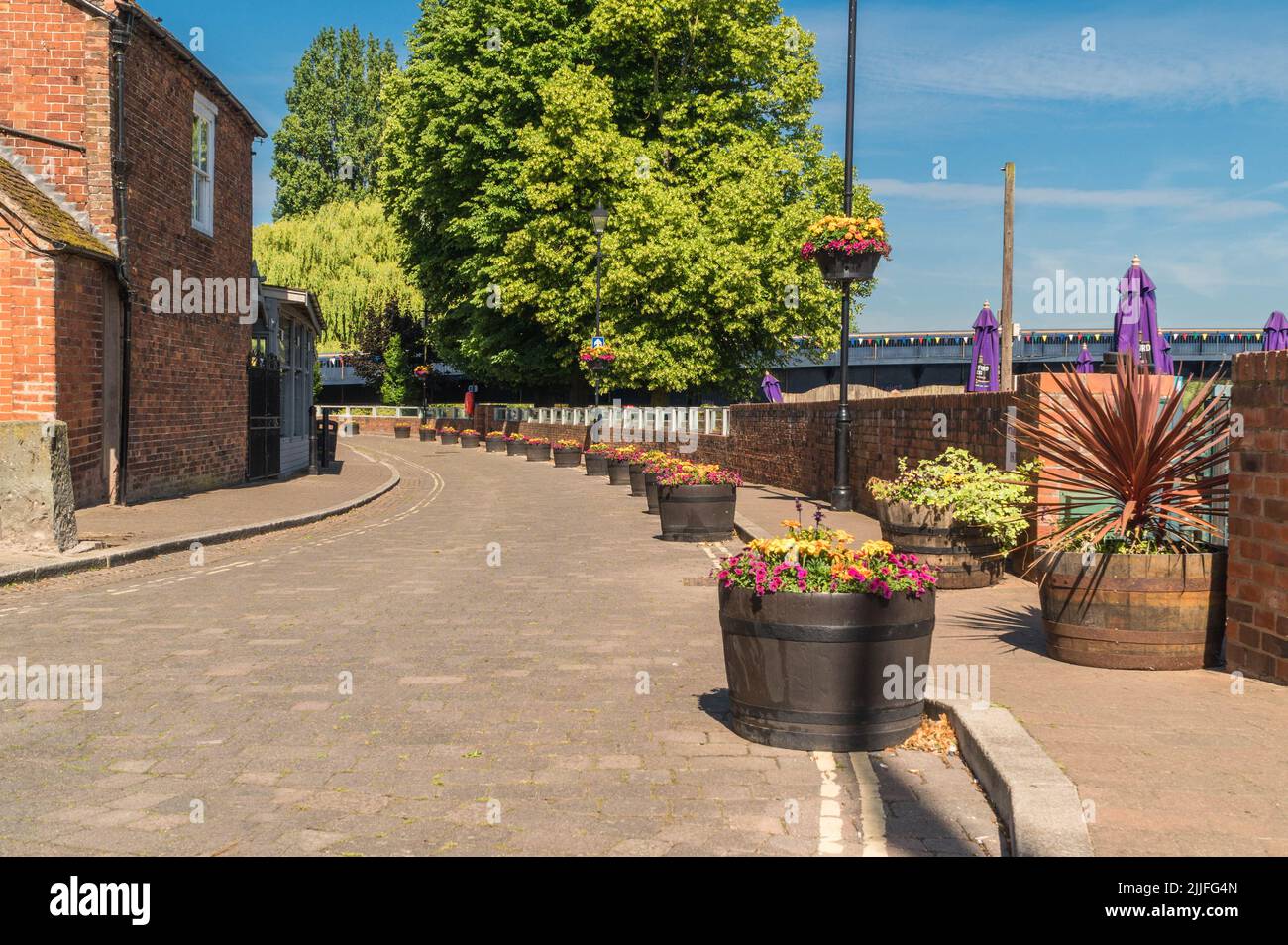 Flower tubs adorn a cobbled riverside walk in the quaint little town of