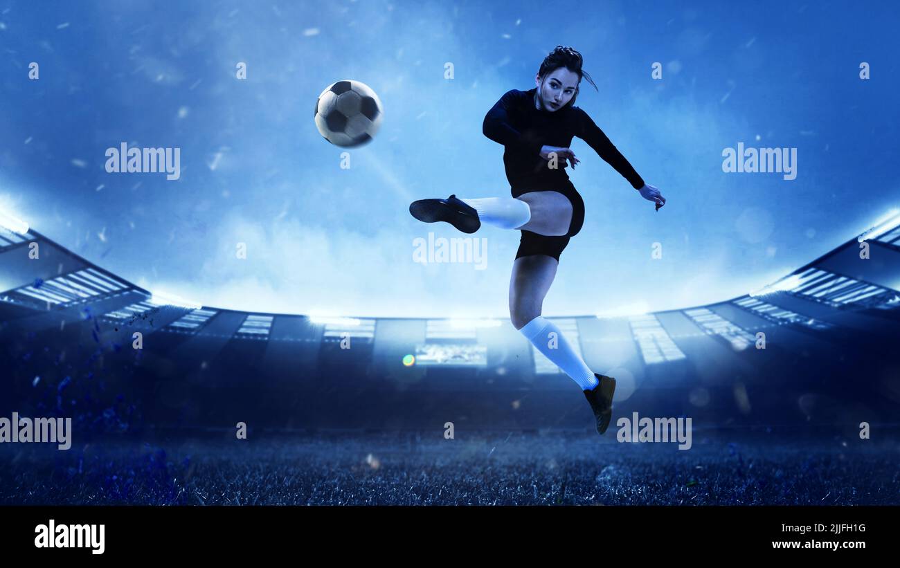 Energetic female soccer or football player in sportwear kicking ball in ...