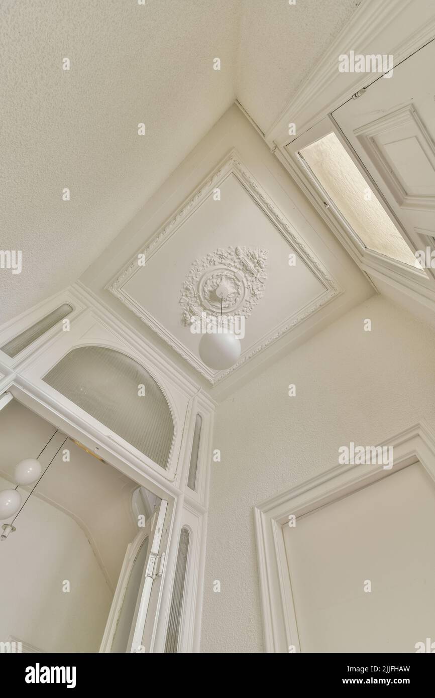 From below classic plaster floral ornament of medallion decorating ceiling above elegant chandelier at home Stock Photo