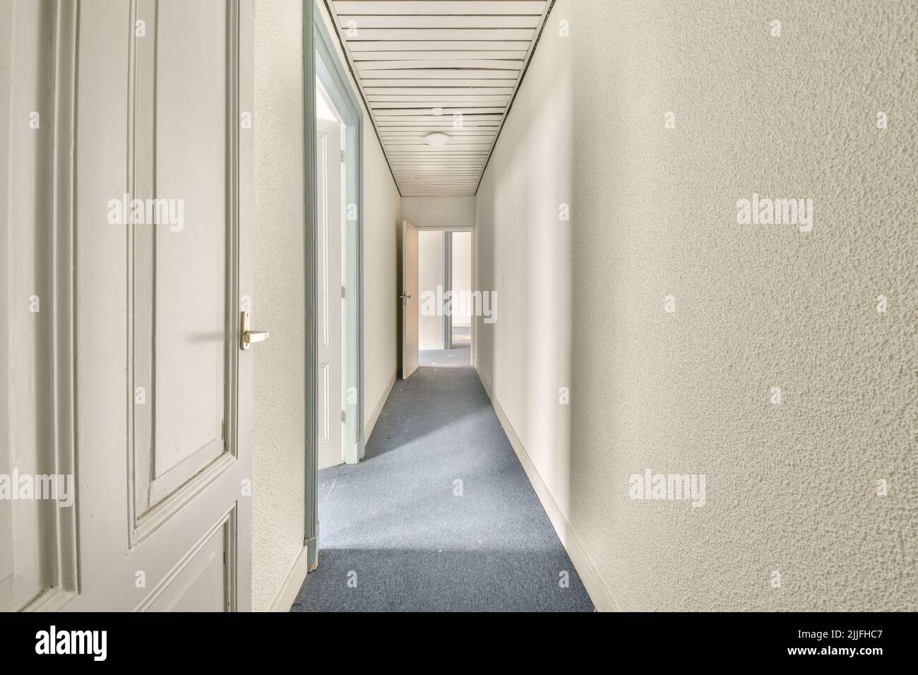 Interior of modern flat in minimal style with narrow empty corridor illuminated by lamps Stock Photo