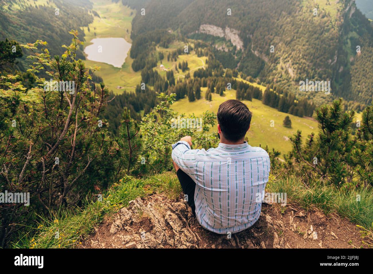 A man sitting on a hill and looking at the Appenzell Alps in Switzerland Stock Photo