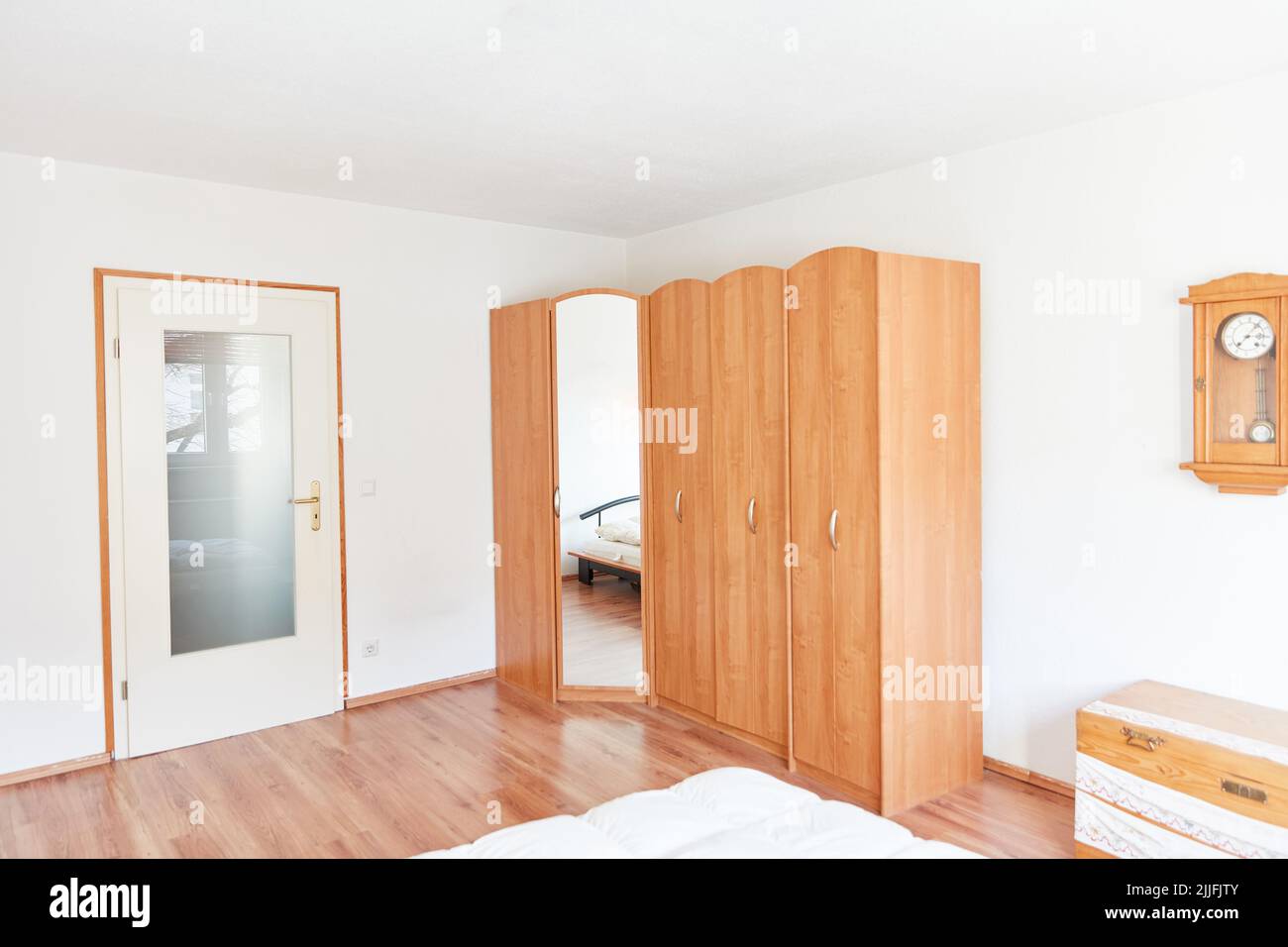 Furnished bedroom with corner wardrobe and mirror in an apartment Stock Photo