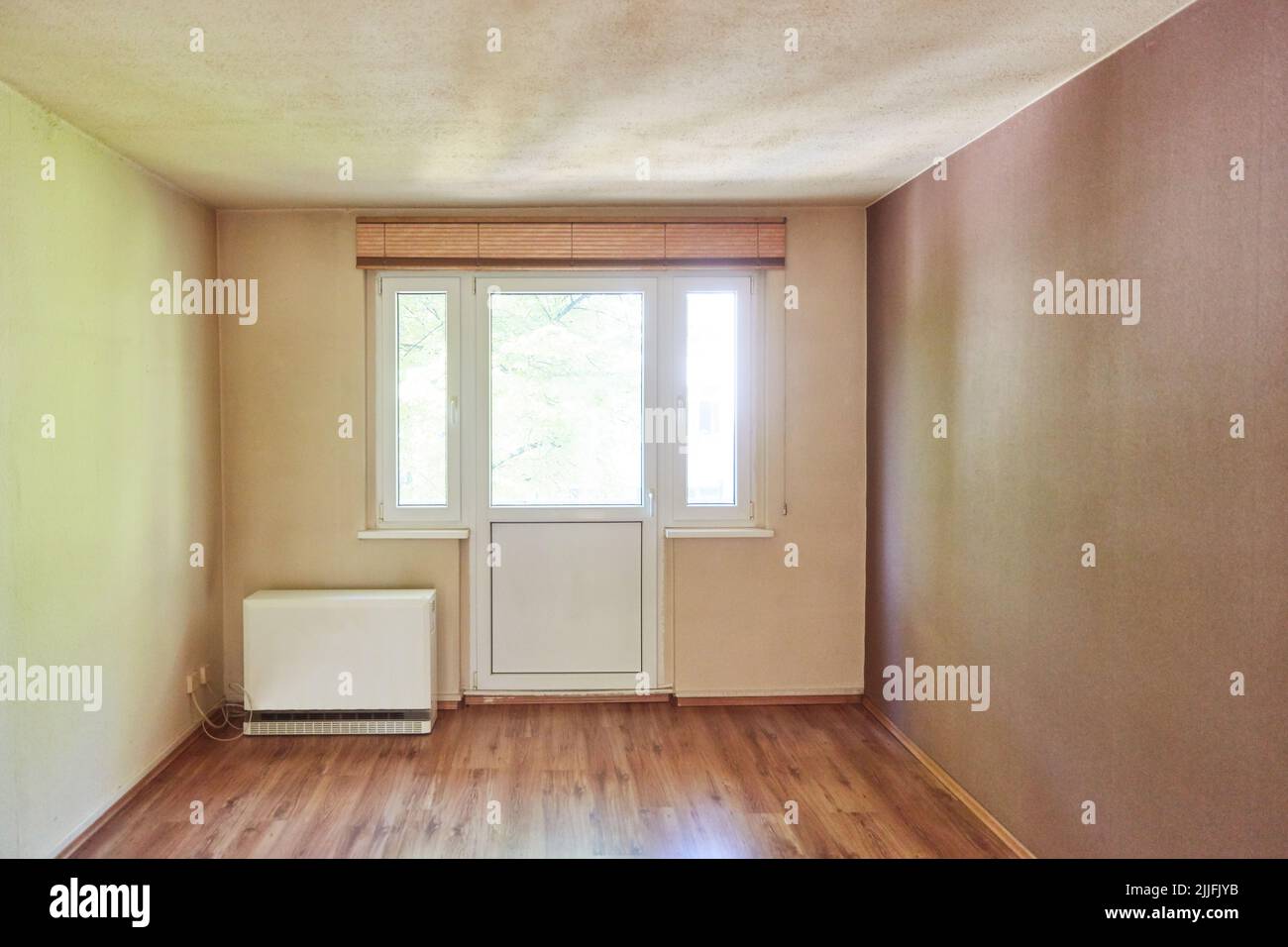 Empty room in need of renovation with balcony door and night storage heater Stock Photo