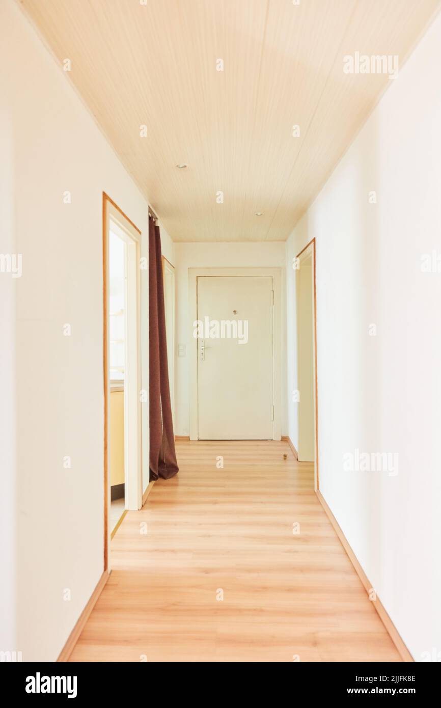 View through a bright, long, narrow hallway to the apartment door Stock Photo