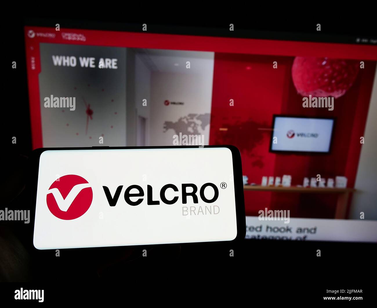 Person holding smartphone with logo of British company Velcro IP Holdings LLC on screen in front of website. Focus on phone display. Stock Photo