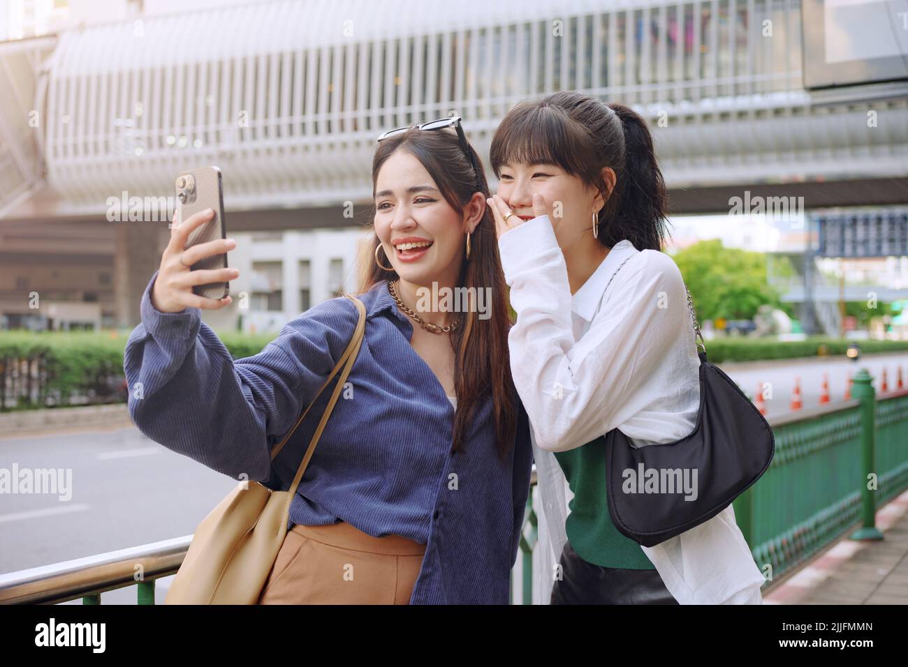 Happy two young women make selfie video call with her friend on city street. Stock Photo