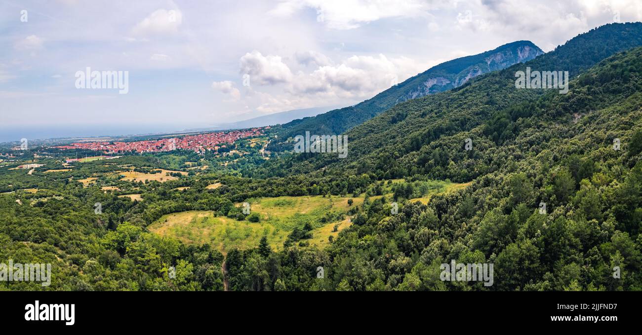 Mount Olympus, Greece. Small Greek village in the background. Forest hills and cloudy sky. Panoramic drone aerial shot. High quality photo Stock Photo