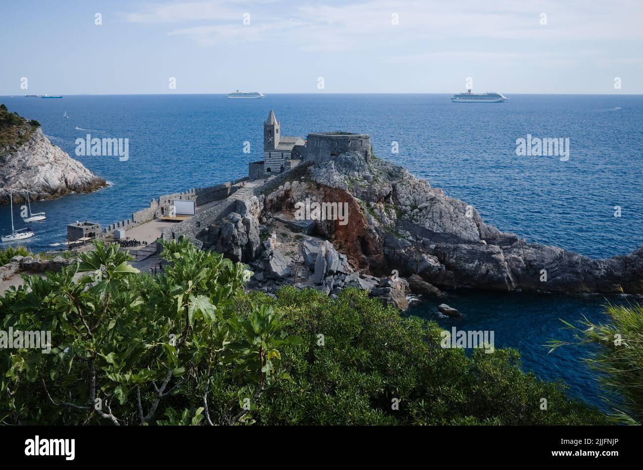 View of Chiesa San Pietro or St. Peter Church in Porto Venere, Liguria, Italy. View of medieval church on rock by sea. Cruise ships are on horizon Stock Photo