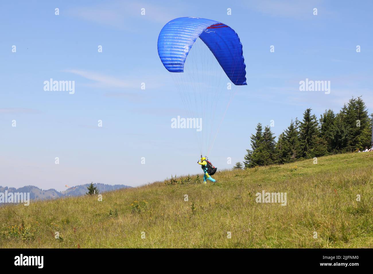 A paraglider taking off from the alpine summit Baumgartenalpe in Austria. Stock Photo