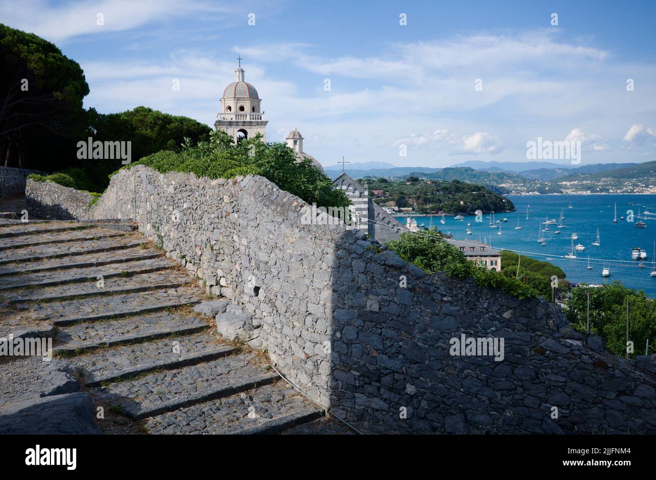Panoramic view to bay with many yachts from stone steps and remains of medieval stone wall in Porto Venere, Italy. Dome of San Lorenzo church Stock Photo