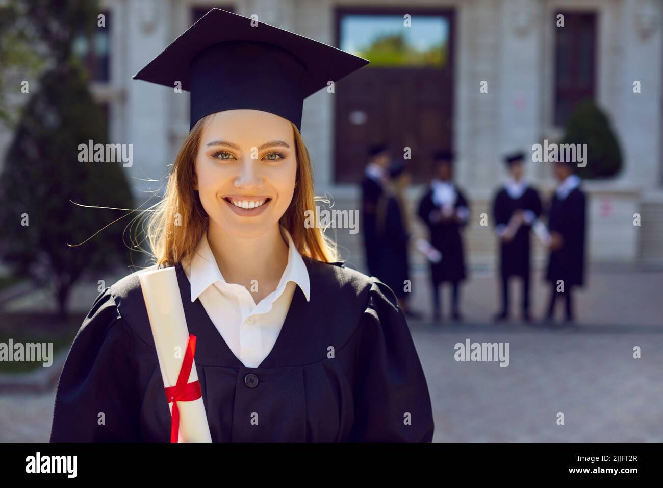 Portrait of happy beautiful student girl outside university after graduation event Stock Photo