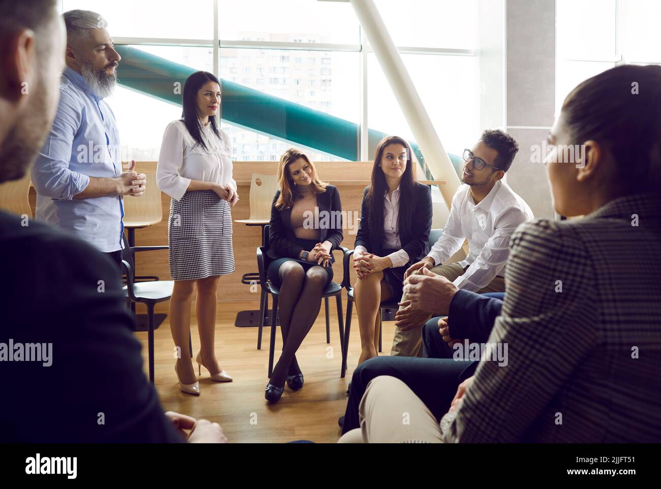 Group of diverse group of business people meeting in office sitting in circle on chairs. Stock Photo