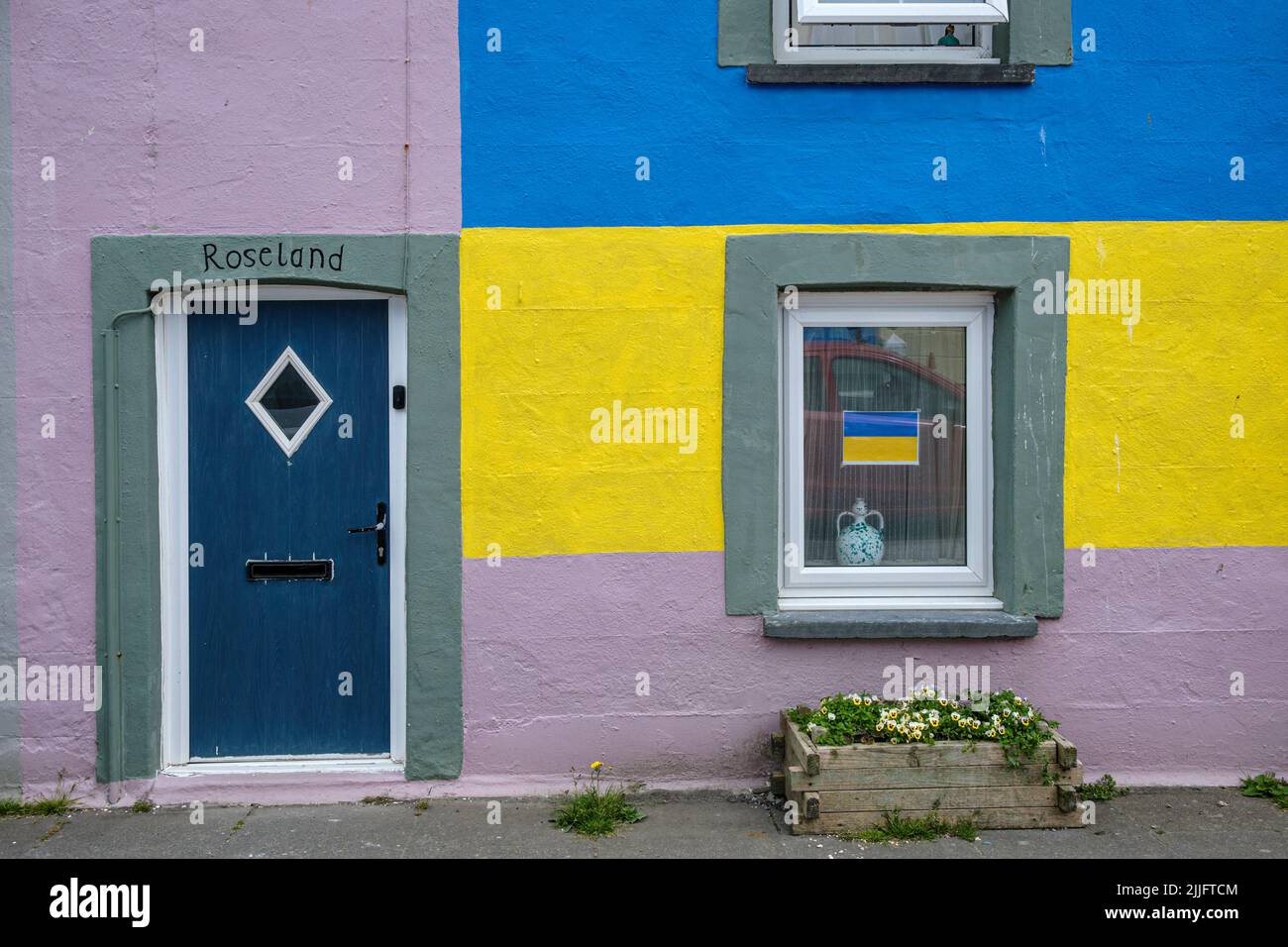 Colourfully painted house with the colours of the Ukraine flag, Borth, Ceredigion, Wales Stock Photo