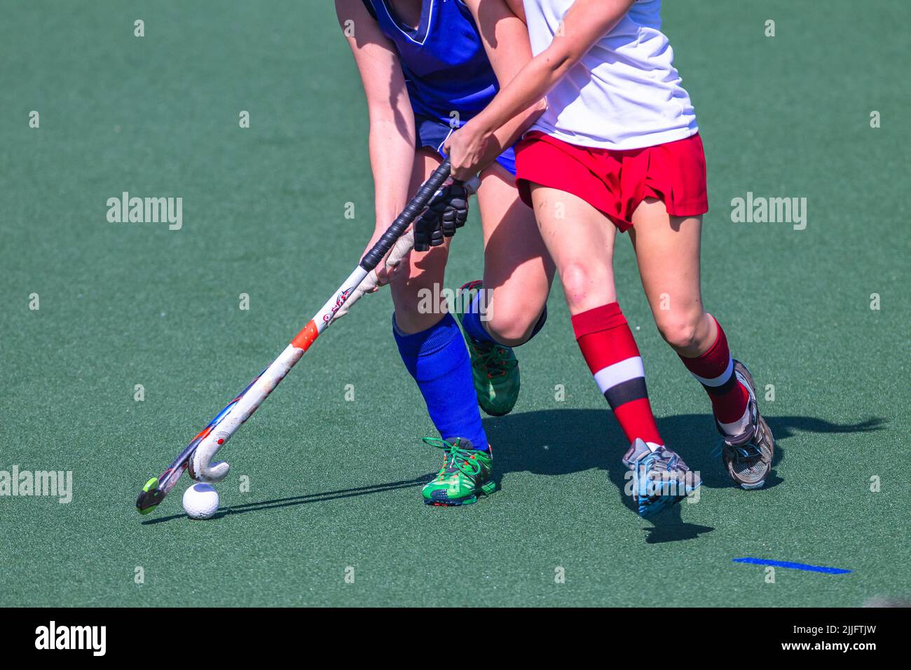 Hockey game girl players decapitated challenge for ball on astro turf