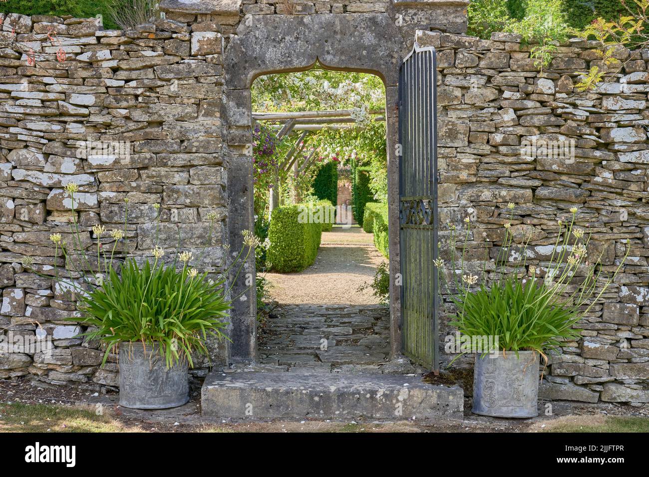 Entrance way to a large garden through a Cotswoild stone wall Stock Photo