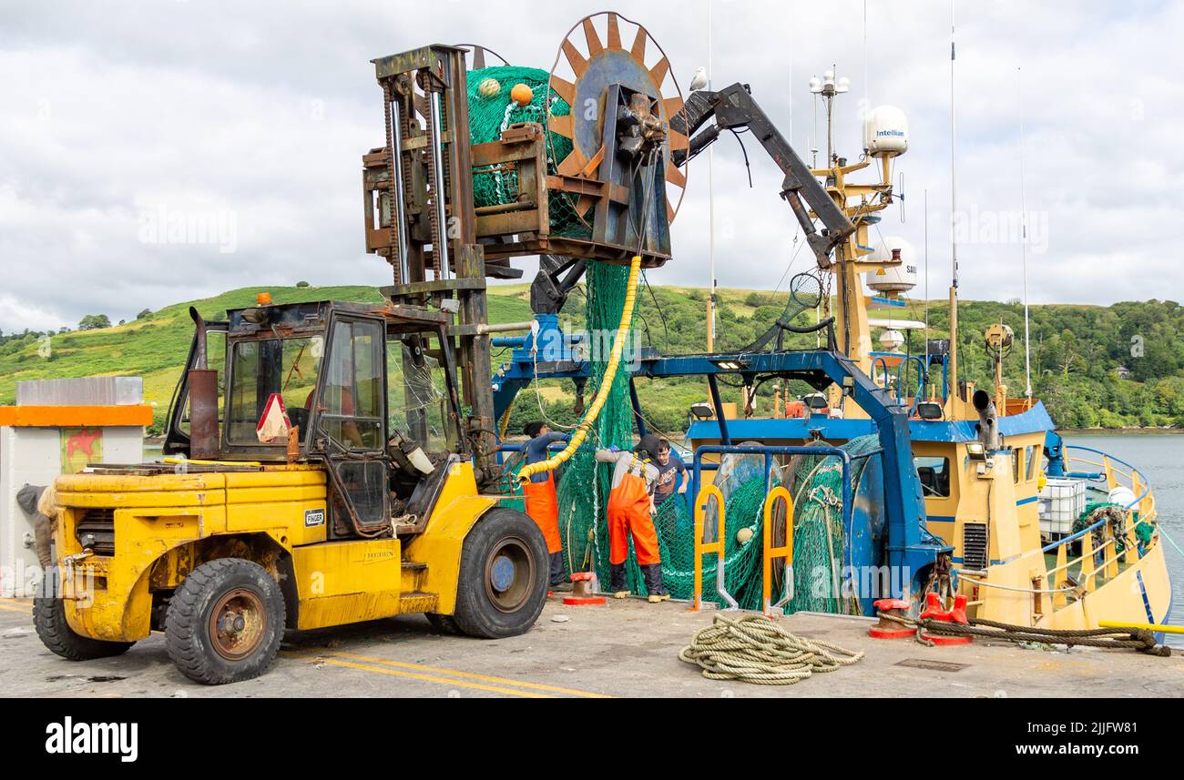 Fishing Trawler loading nets onboard from a reel on forklift truck Stock Photo