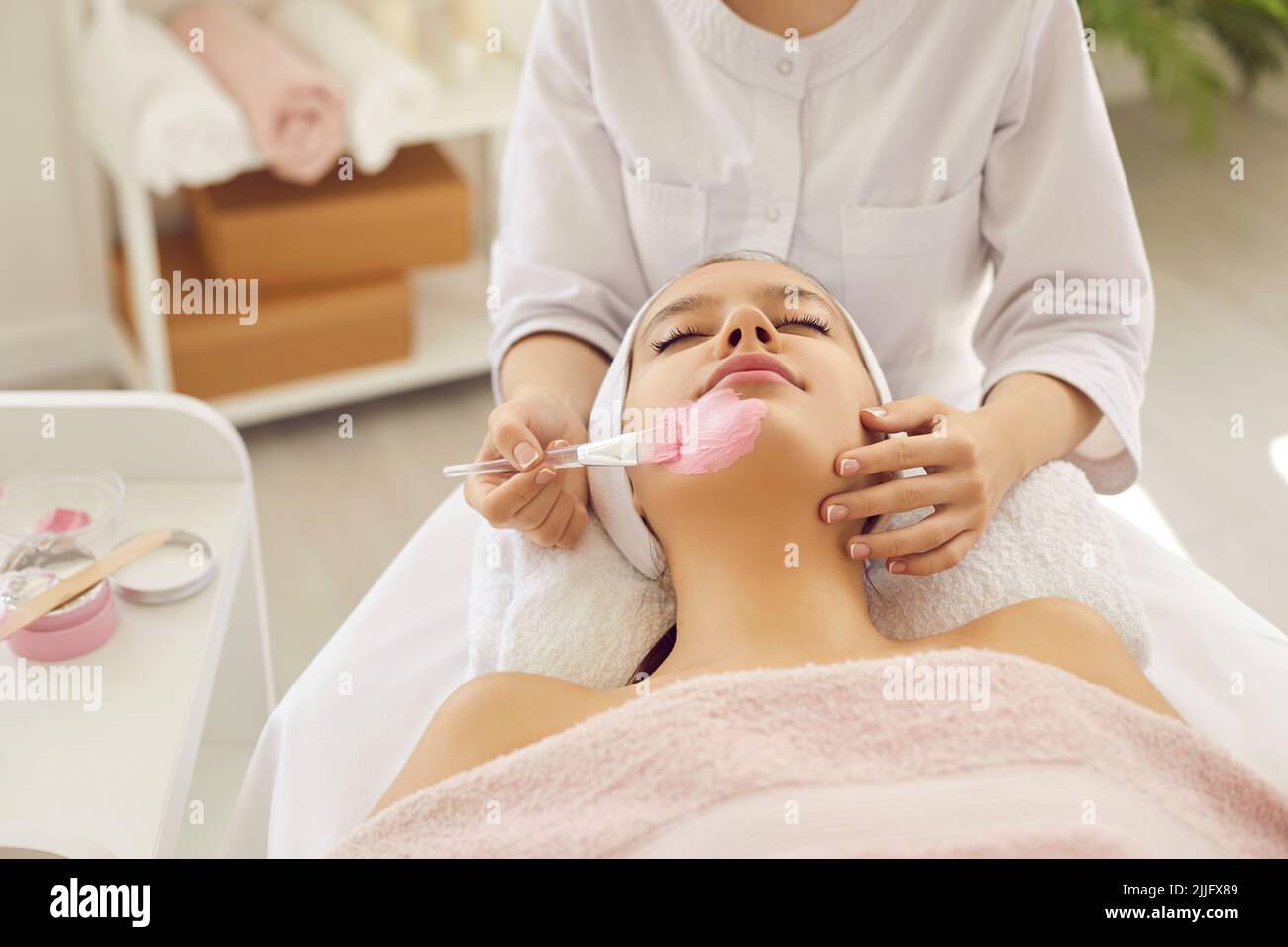Woman enjoying clay mask while getting facial treatment in spa salon or beauty parlor Stock Photo