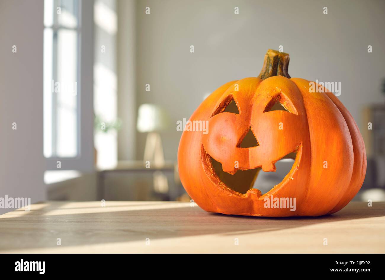 Festive Halloween background with a funny smiley carved pumpkin on a table at home Stock Photo