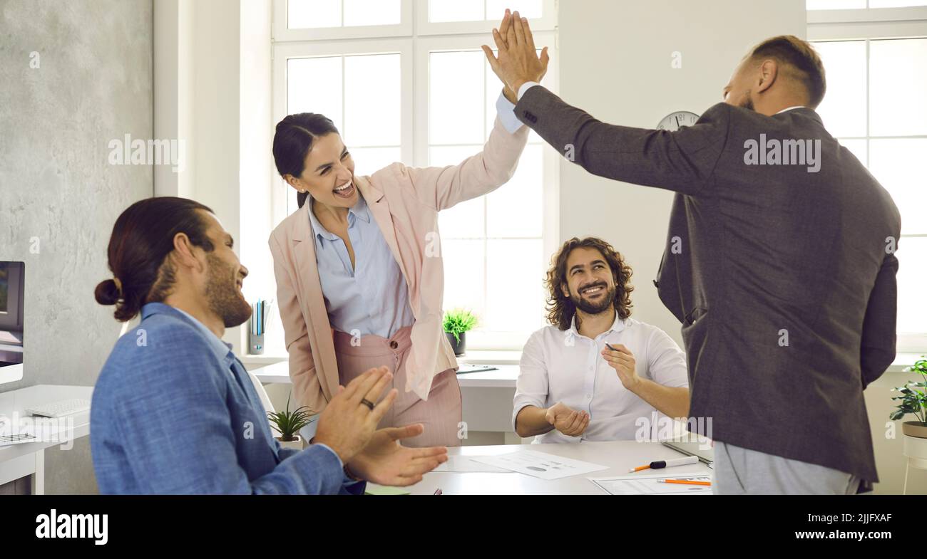 Group of happy young people making a business deal and giving each other a high five Stock Photo