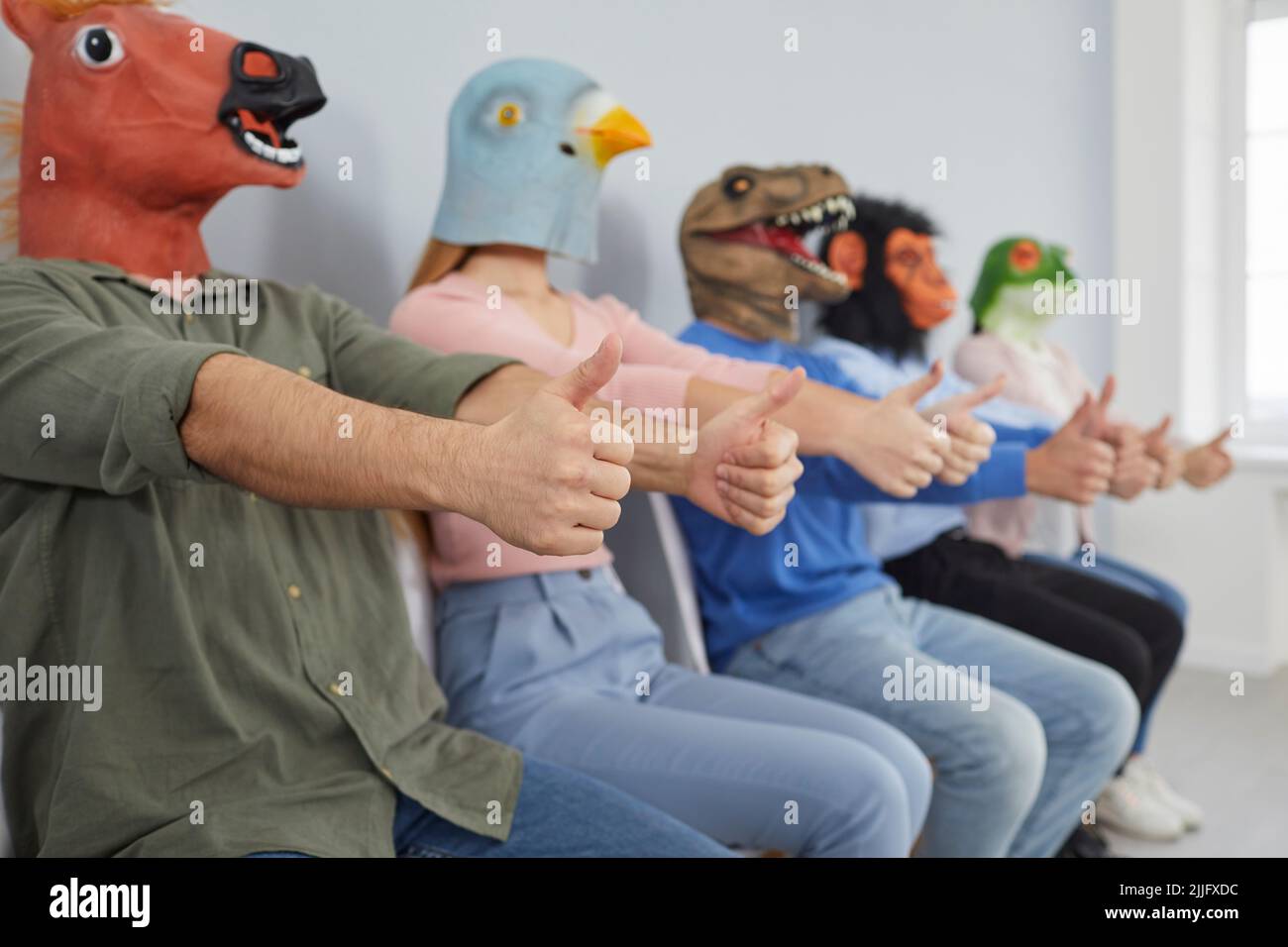 Group of strange men and women wearing funny animal masks giving thumbs up together Stock Photo