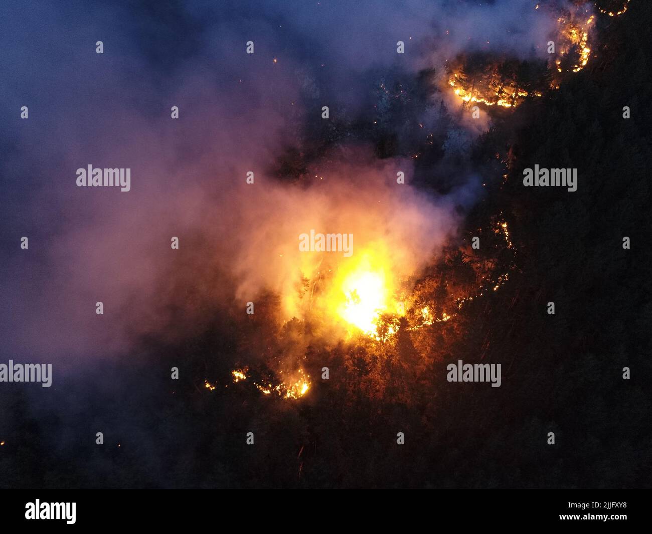 Aerial panoramic view of a forest fire at night, heavy smoke causes air ...