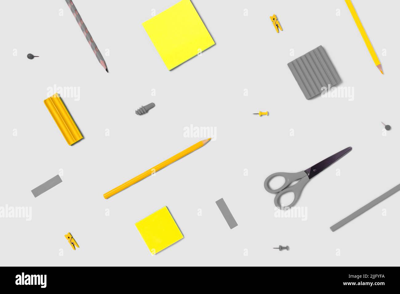 Flat lay photo with stikers, pencils, scissors, plasticine, clothespins, paper clips in yellow and gray colors. Stock Photo