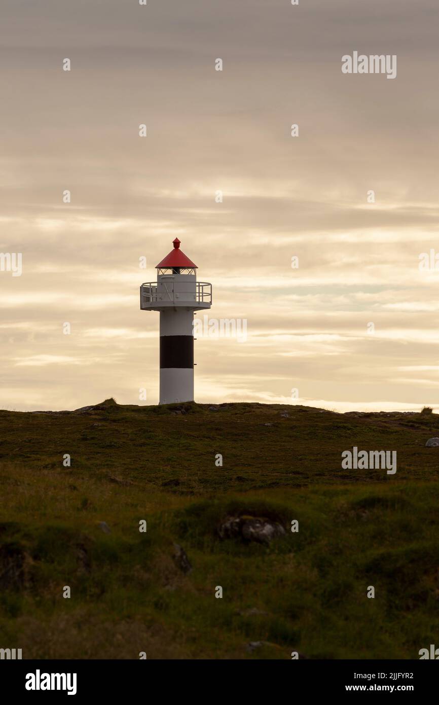 A lighthouse on a hill and a sunset and a cloudy sky in the background. Stock Photo