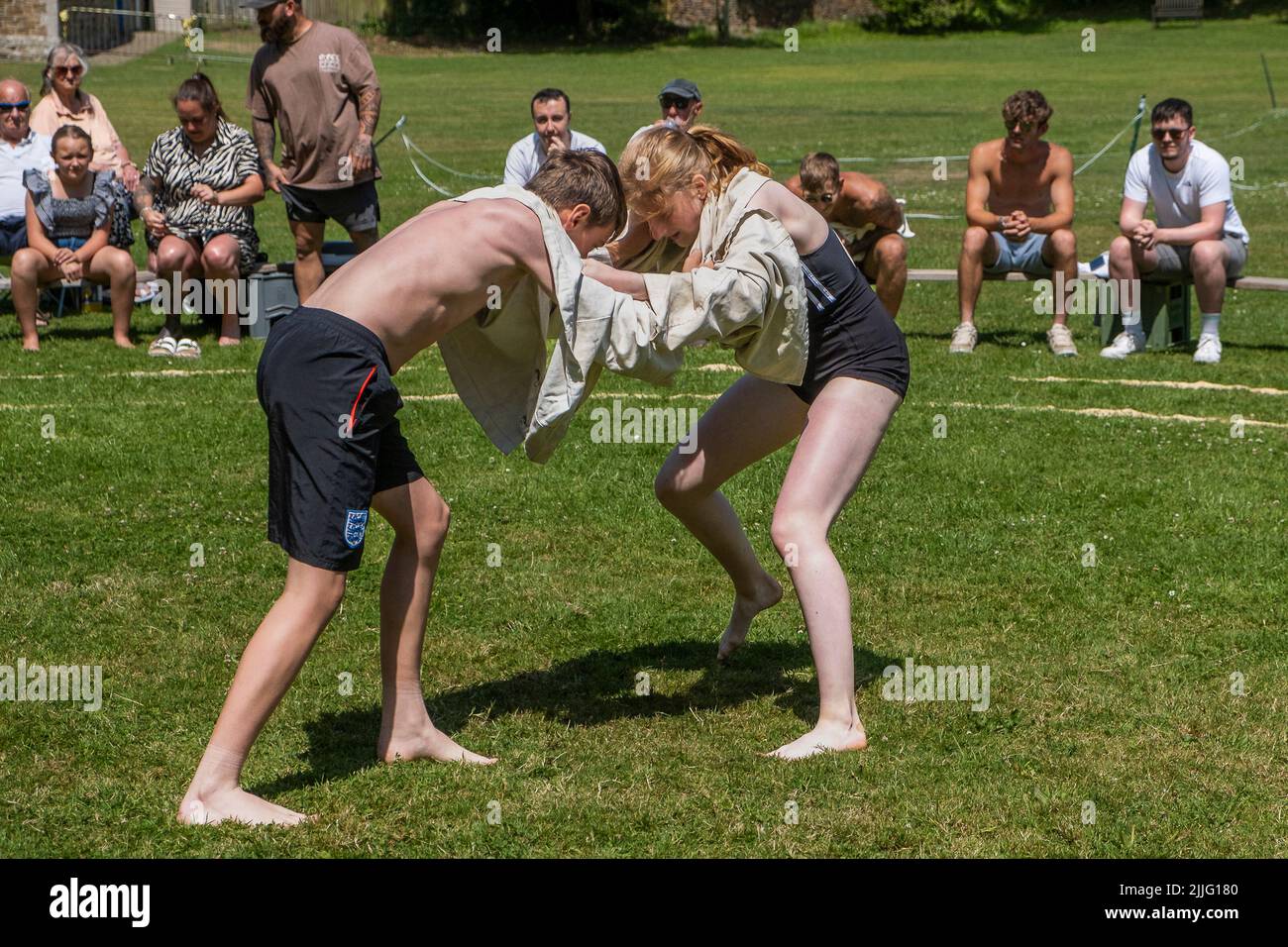 A young teenage girl wrestling with a boy competing in the Grand Cornish Wrestling Tournament on the picturesque village green of St Mawgan in Pydar i Stock Photo