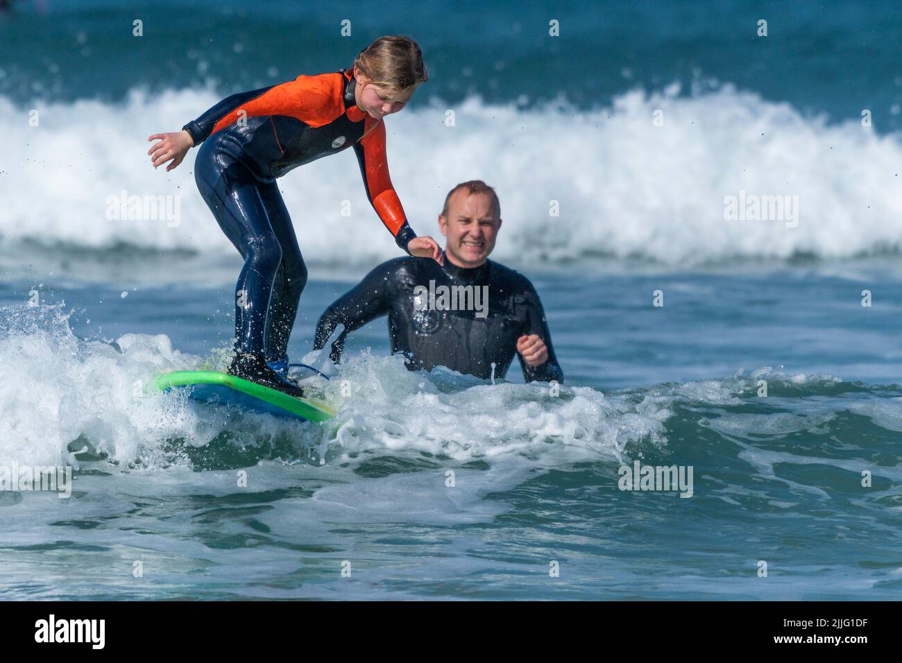 Georgina Fletcher aged 10 from St Austell learning to surf as her proud father watches on at Fistral Beach in Newquay during unseasonably warm weather Stock Photo